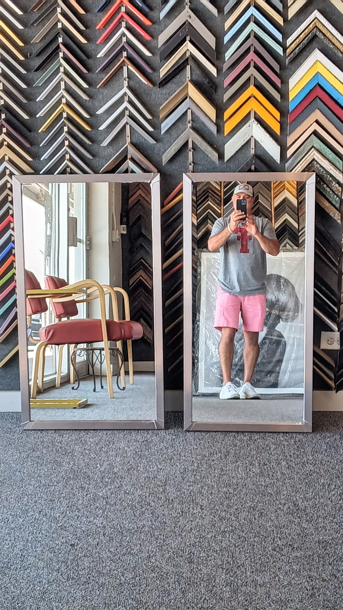 Two large silver-framed floor mirrors in the Uncommon shop, in front of the moulding sample wall