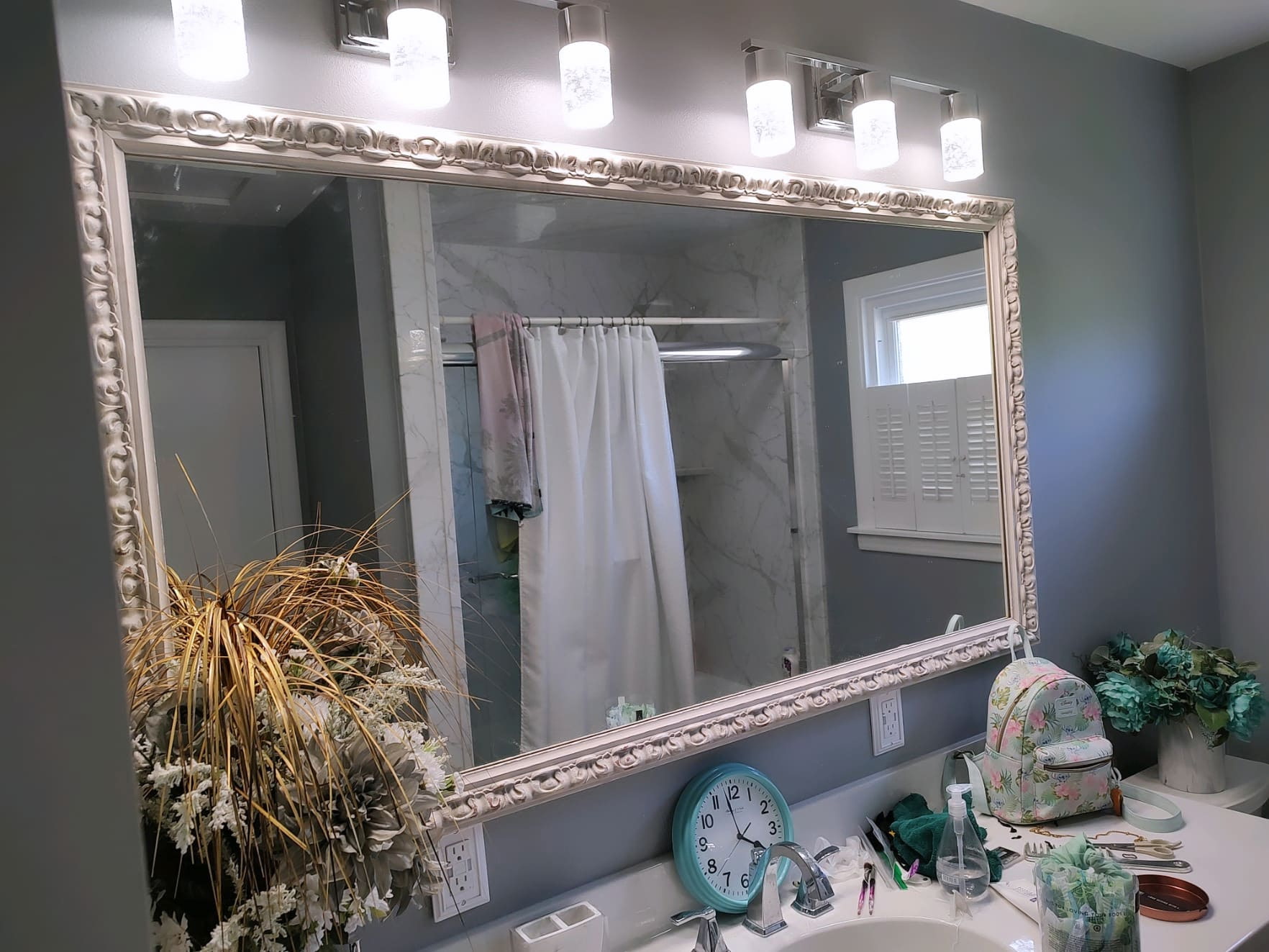 Ornate cream carved frame around a bathroom vanity mirror