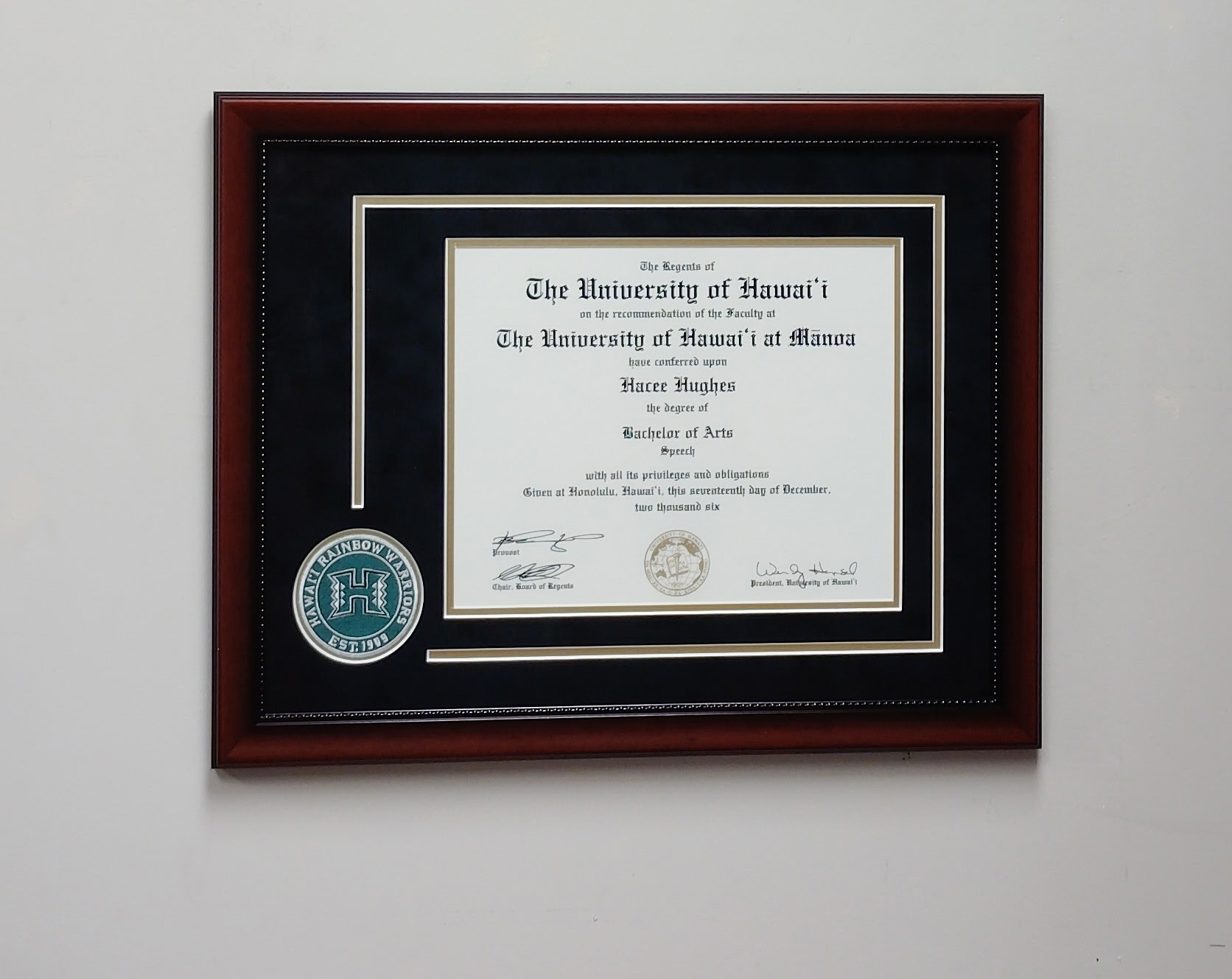 University of Hawaiʻi diploma in a dark-wood frame with black mat and Rainbow Warriors emblem
